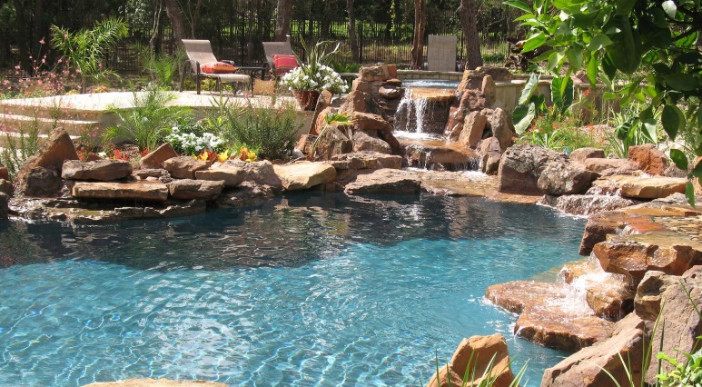 Freeform pool with moss rock waterline and raised spa